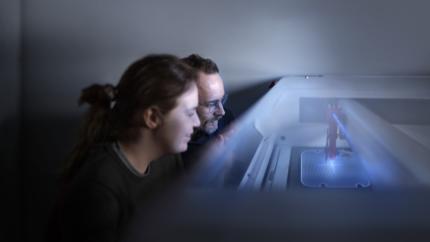 Two people checking a laser cutter.