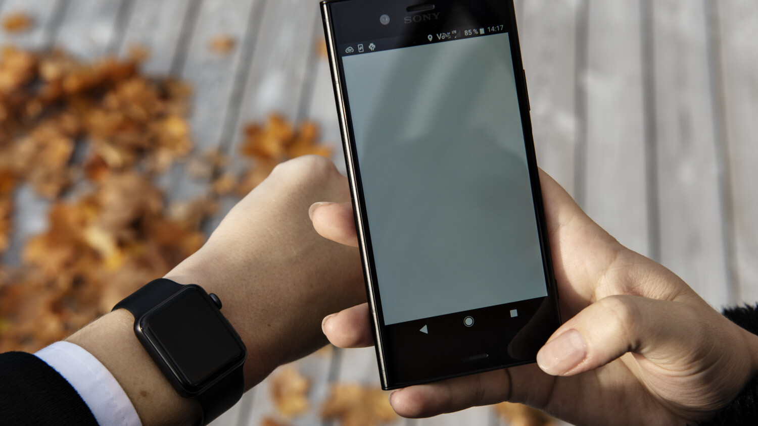 Person holding mobile phone and looking at smart watch.