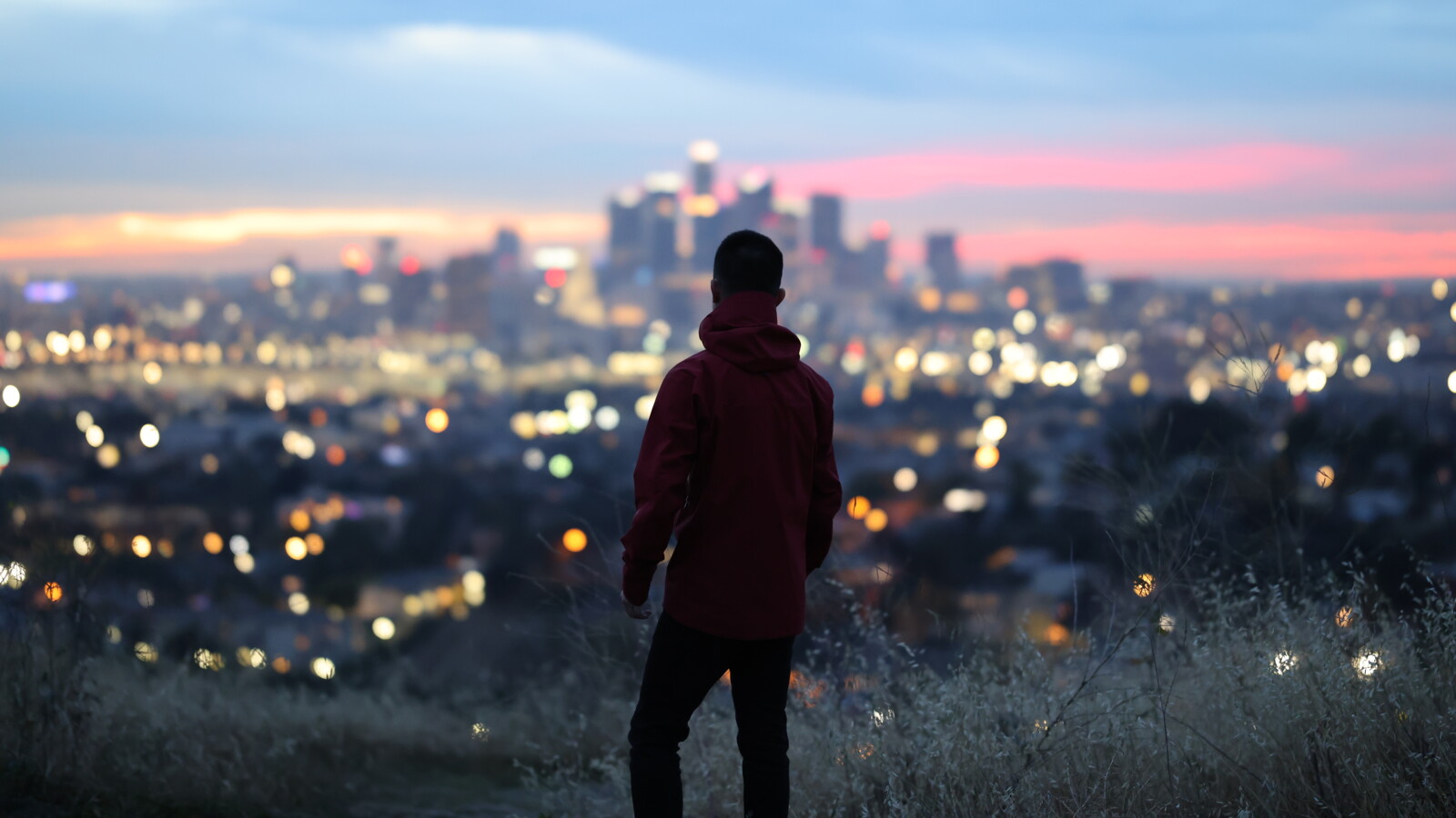 A man  standing in front of an urban area in the dusk.