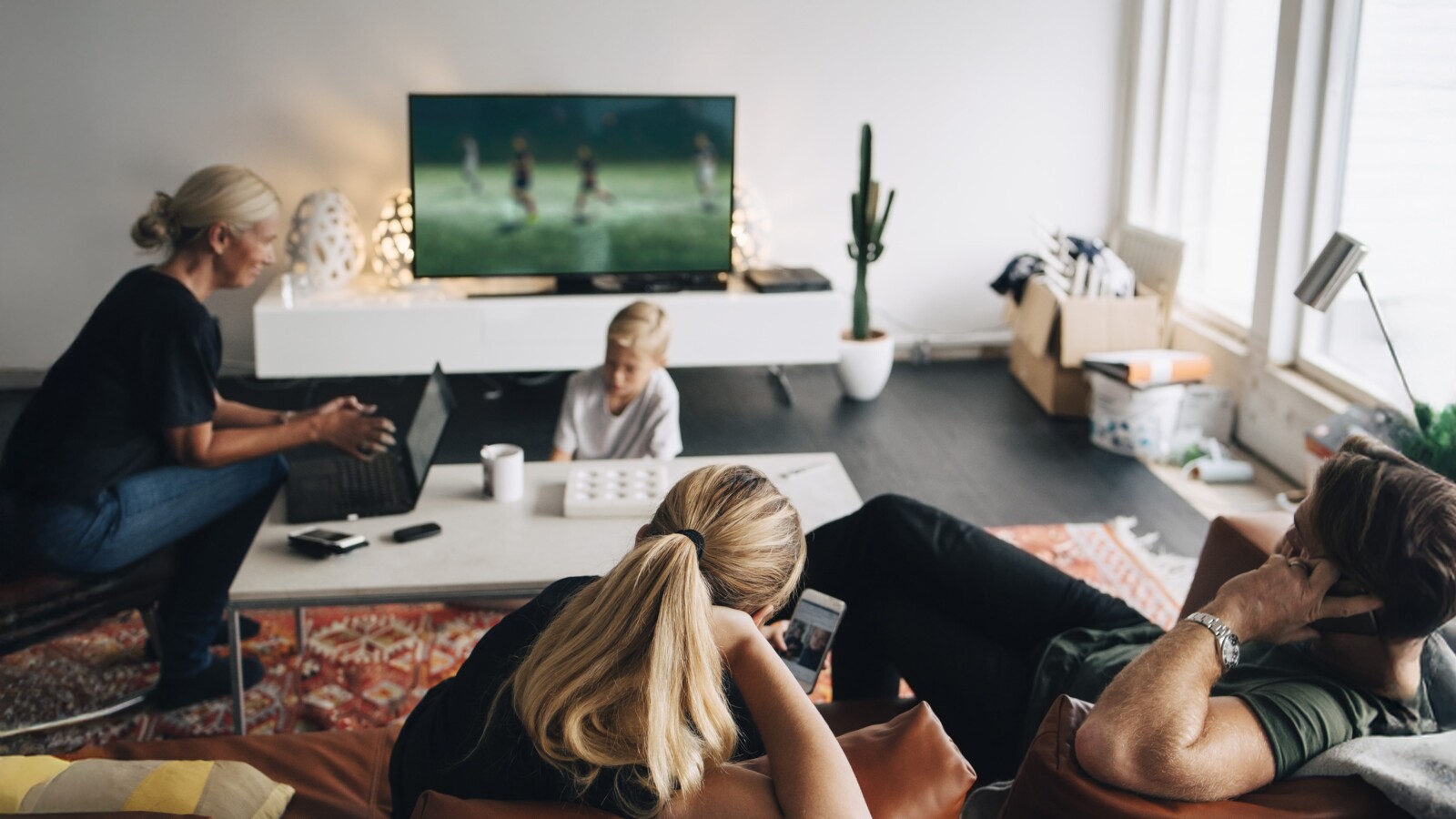 四個人在客廳放鬆，看電視、玩遊戲。