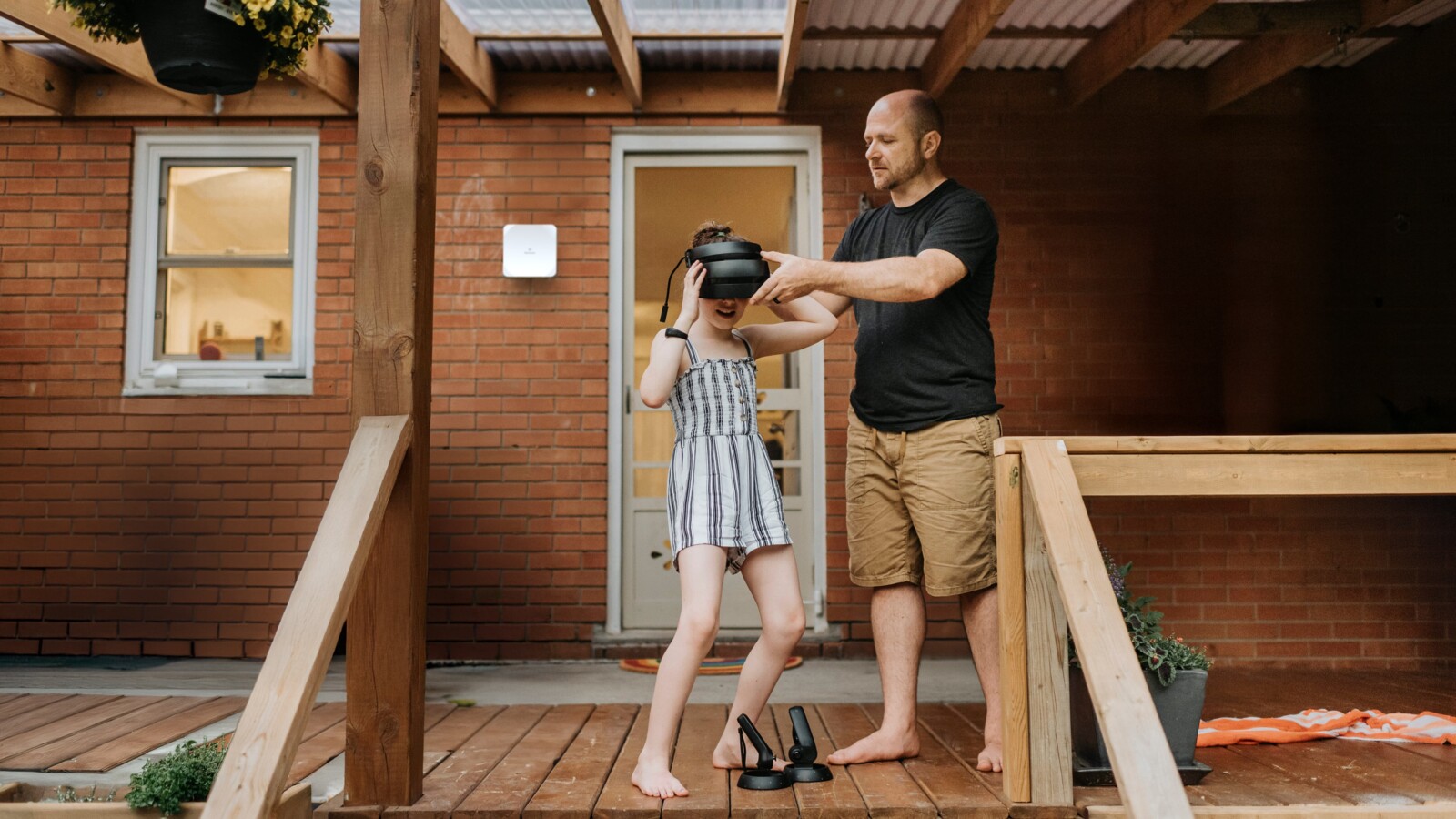 兩個人戴著VR頭顯站在磚房外的甲板上。