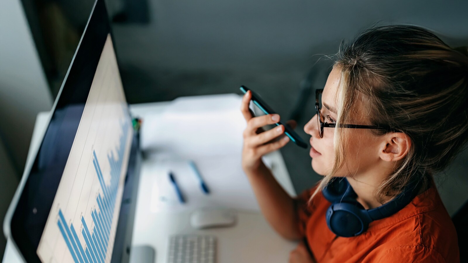 辦公桌前有人一邊看著長條圖一邊打電話。