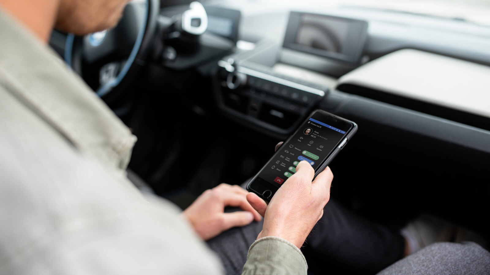 Person holding mobile telephone, sitting in a car.