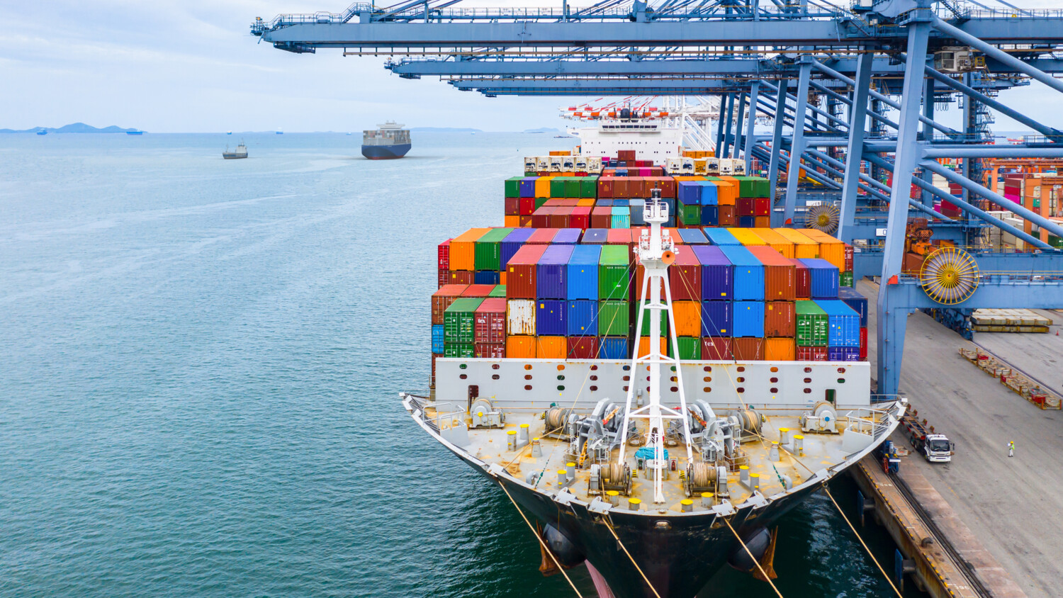 Cargo ship at port with crane and colorful containers.