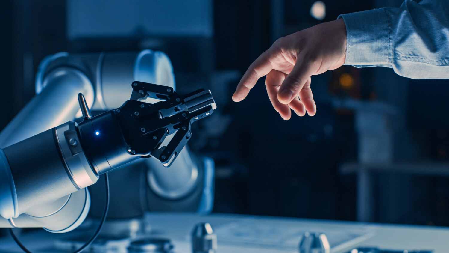 Photo of robot arm and a human hand.