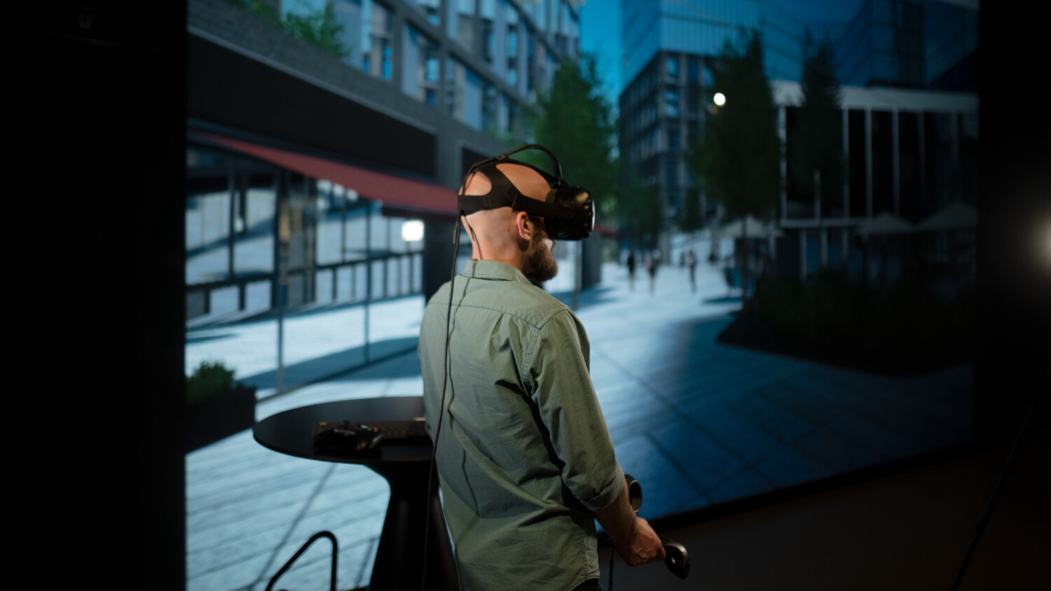 Person using VR in front of large screen.