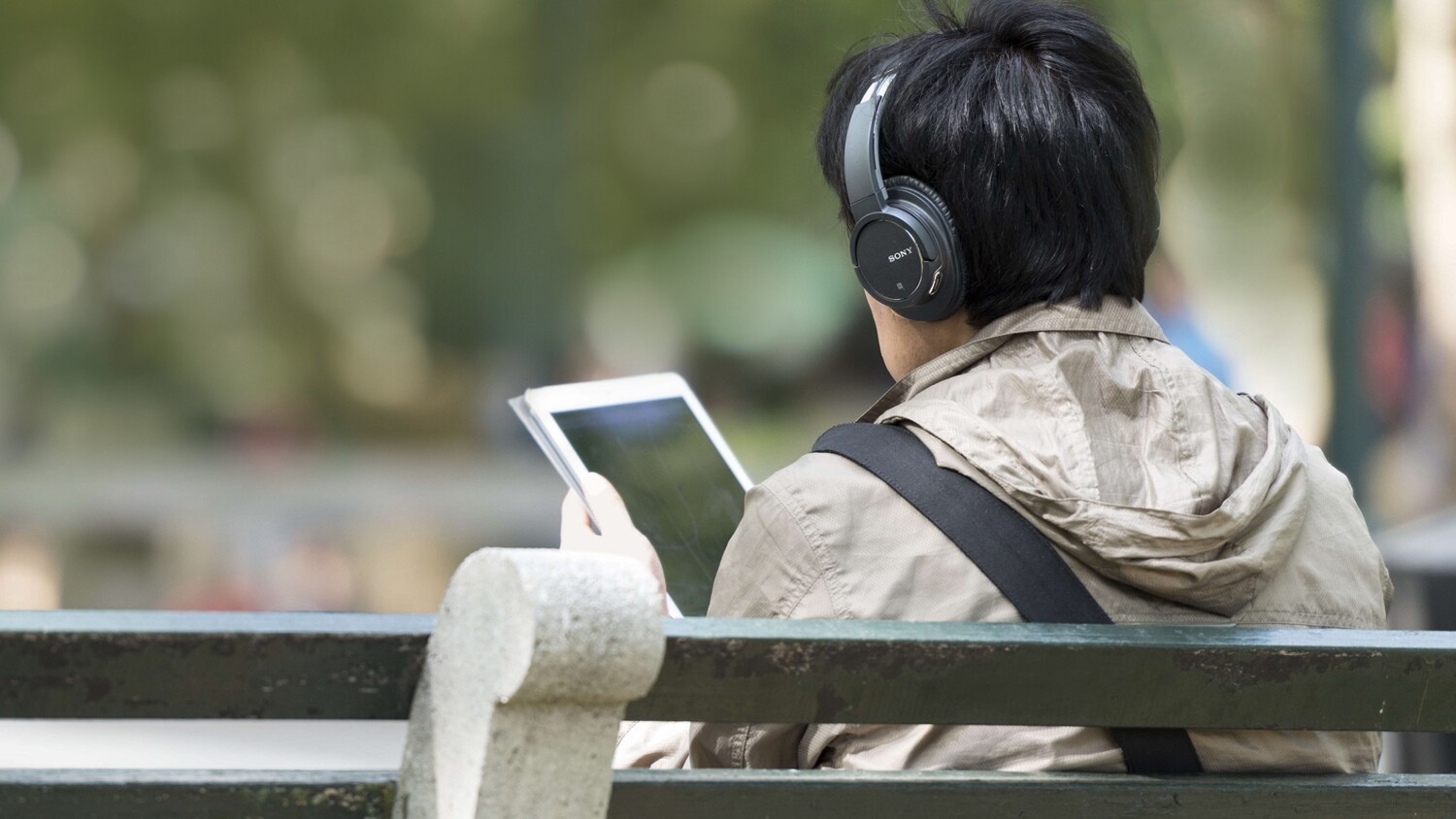 Man sitting on a bench working on tablet
