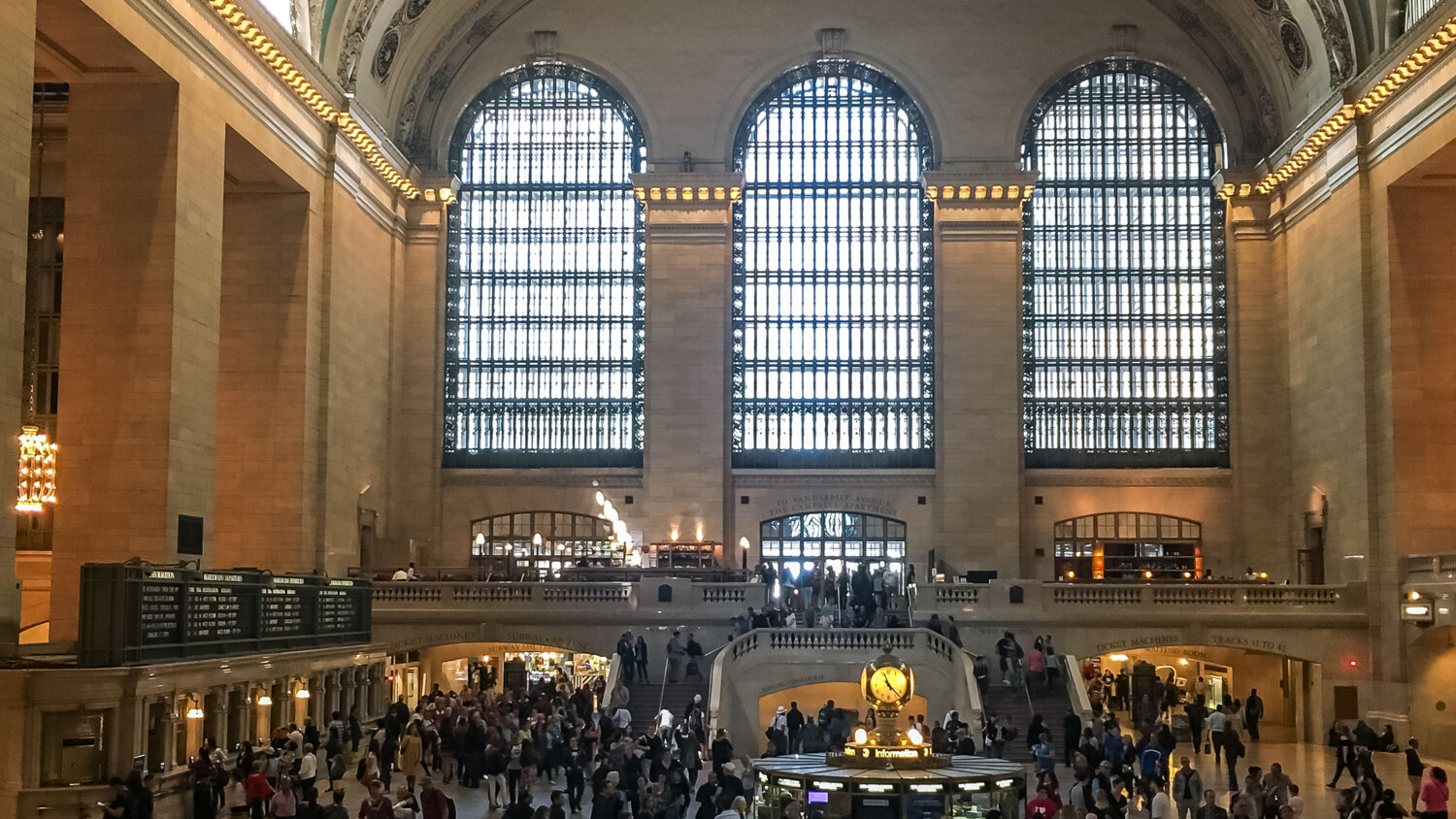 Crowded Grand Central Terminal with iconic clock and windows.
