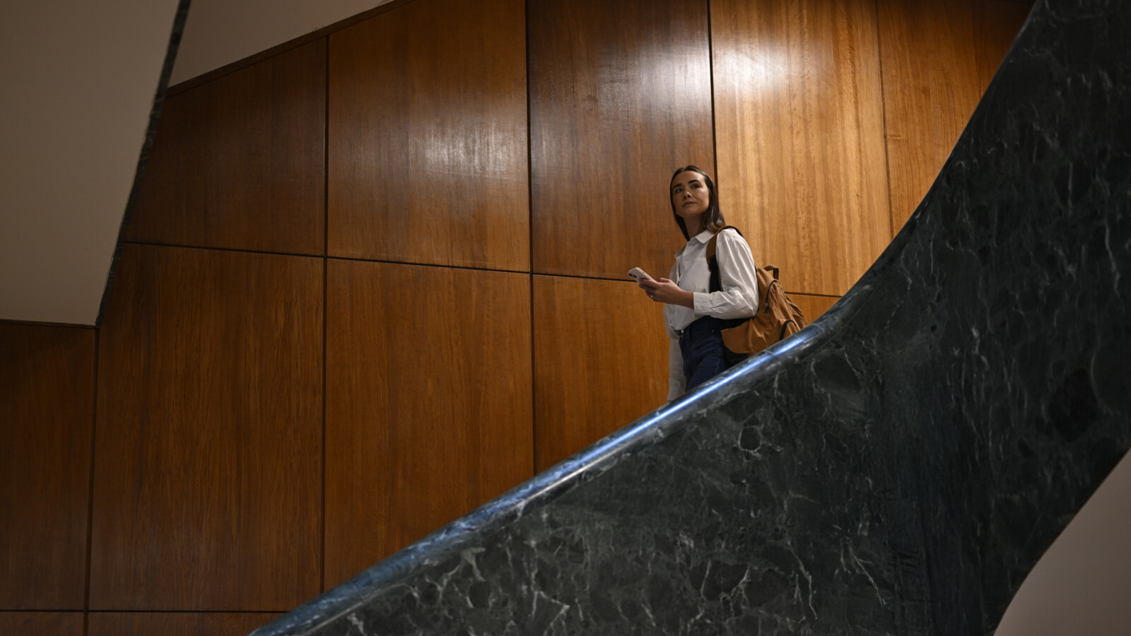 A female student on a staircase with a mobile looking away