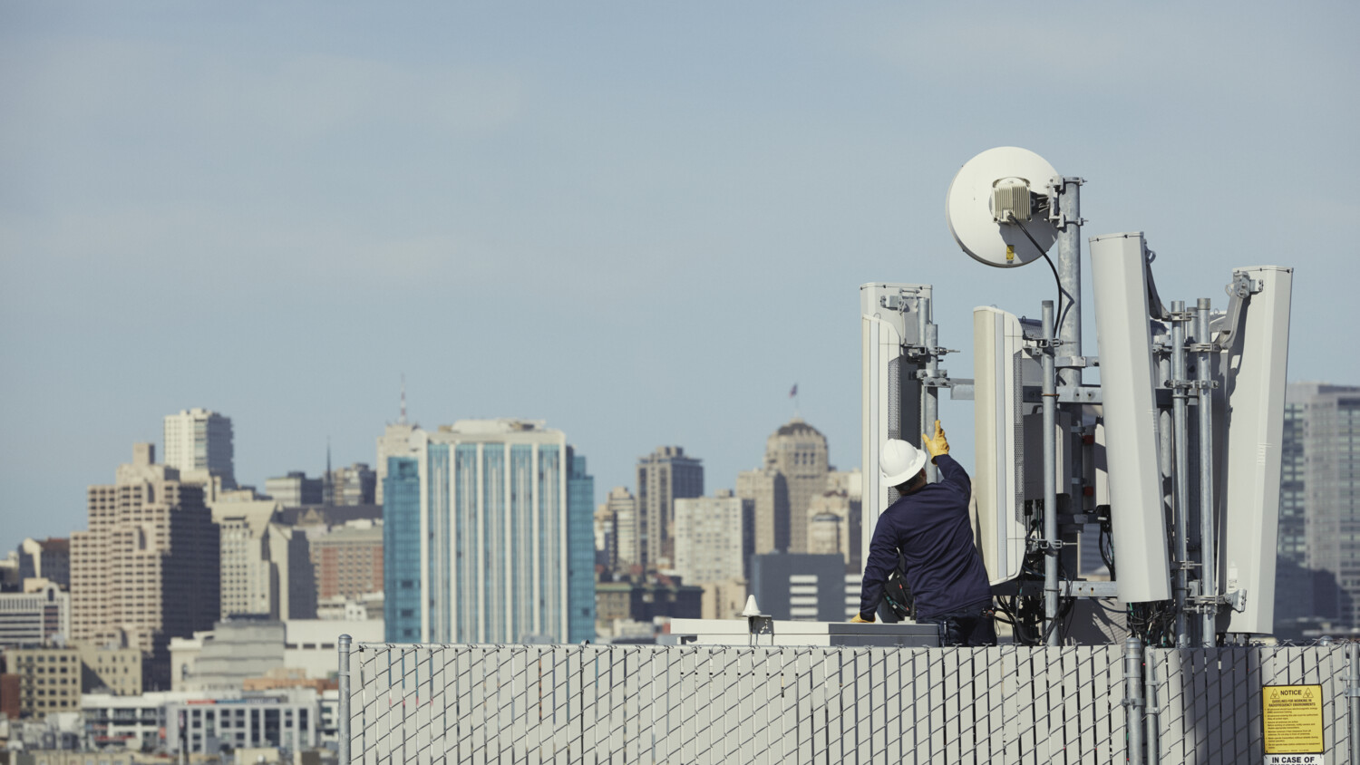 Engineer installing network hardware in urban environment.