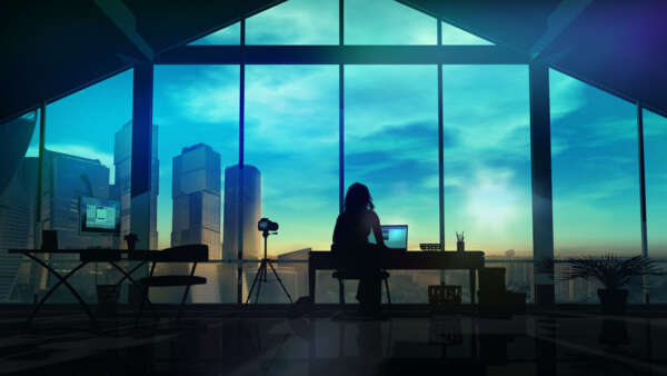 Person sitting in front of a window working on a laptop.