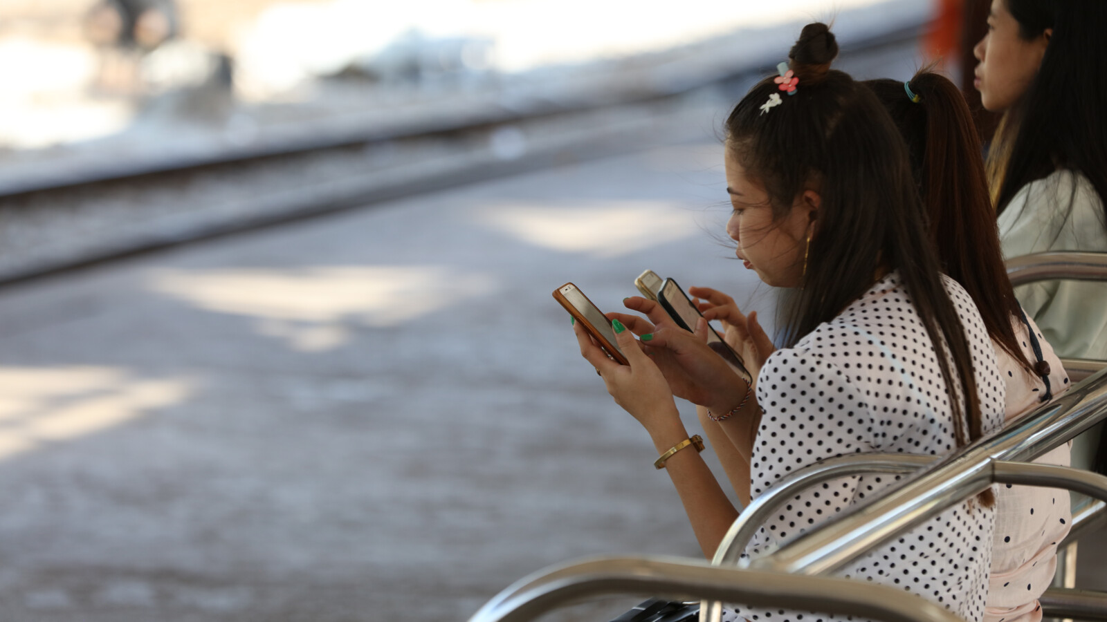 2 young women with smartphone sitting outdoors.