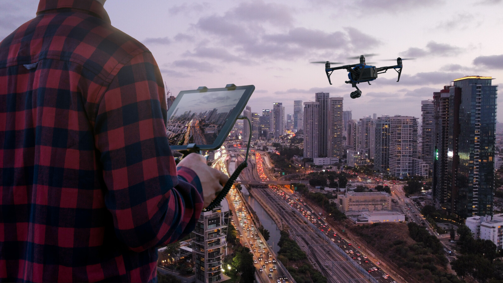 Man using drone to monitor the city night traffic.