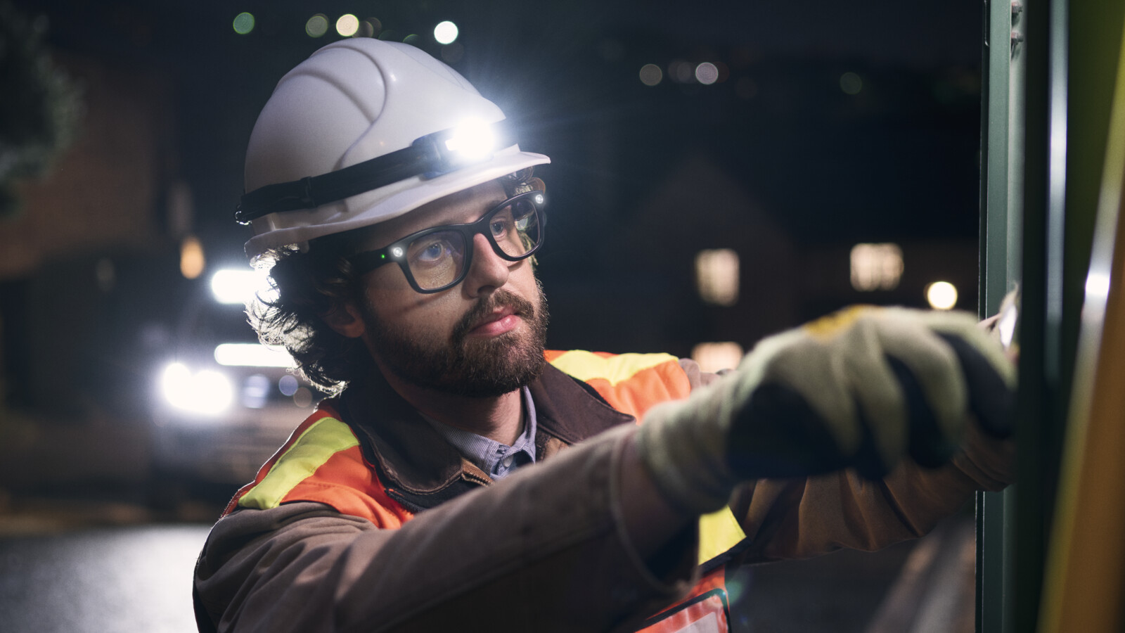 Field technician wearing safety gear working outdoors at night.