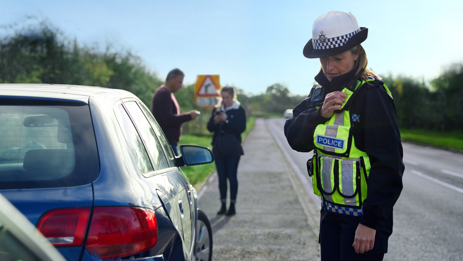 Policewoman using a walkie-talkie by the road side.