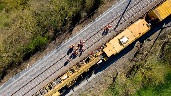 Aerial view of railway workers in near maintenance vehicle on tracks.