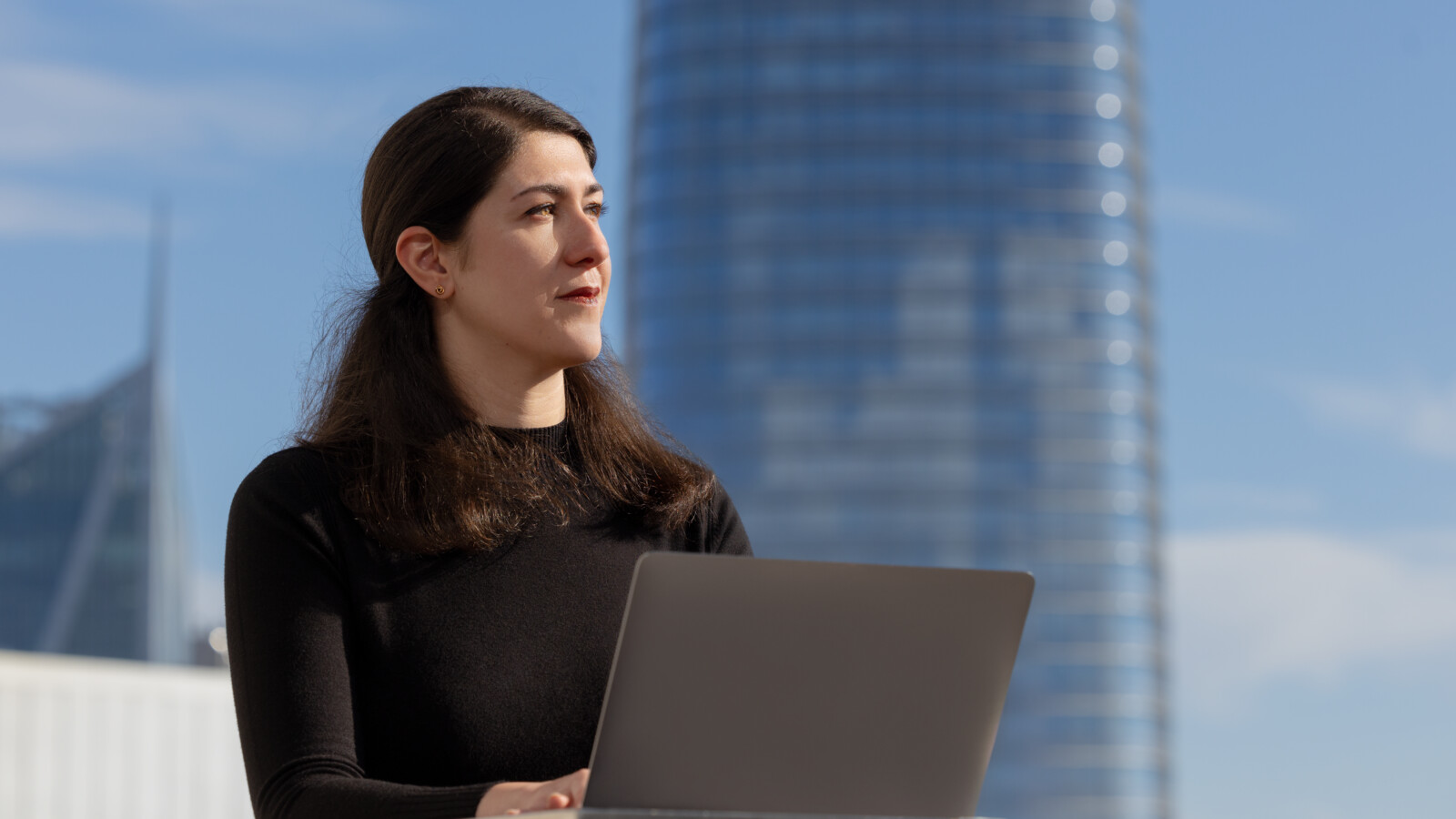 A woman working on her laptop in the city.