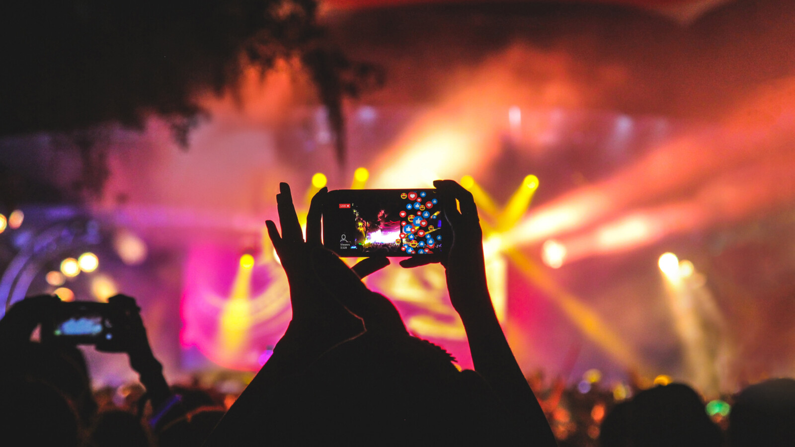Hands holding mobile phone, filming in a concert event.