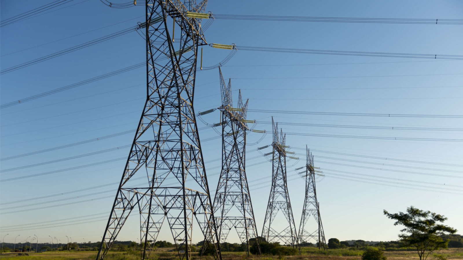 High-voltage power lines and towers in a green open landscape.