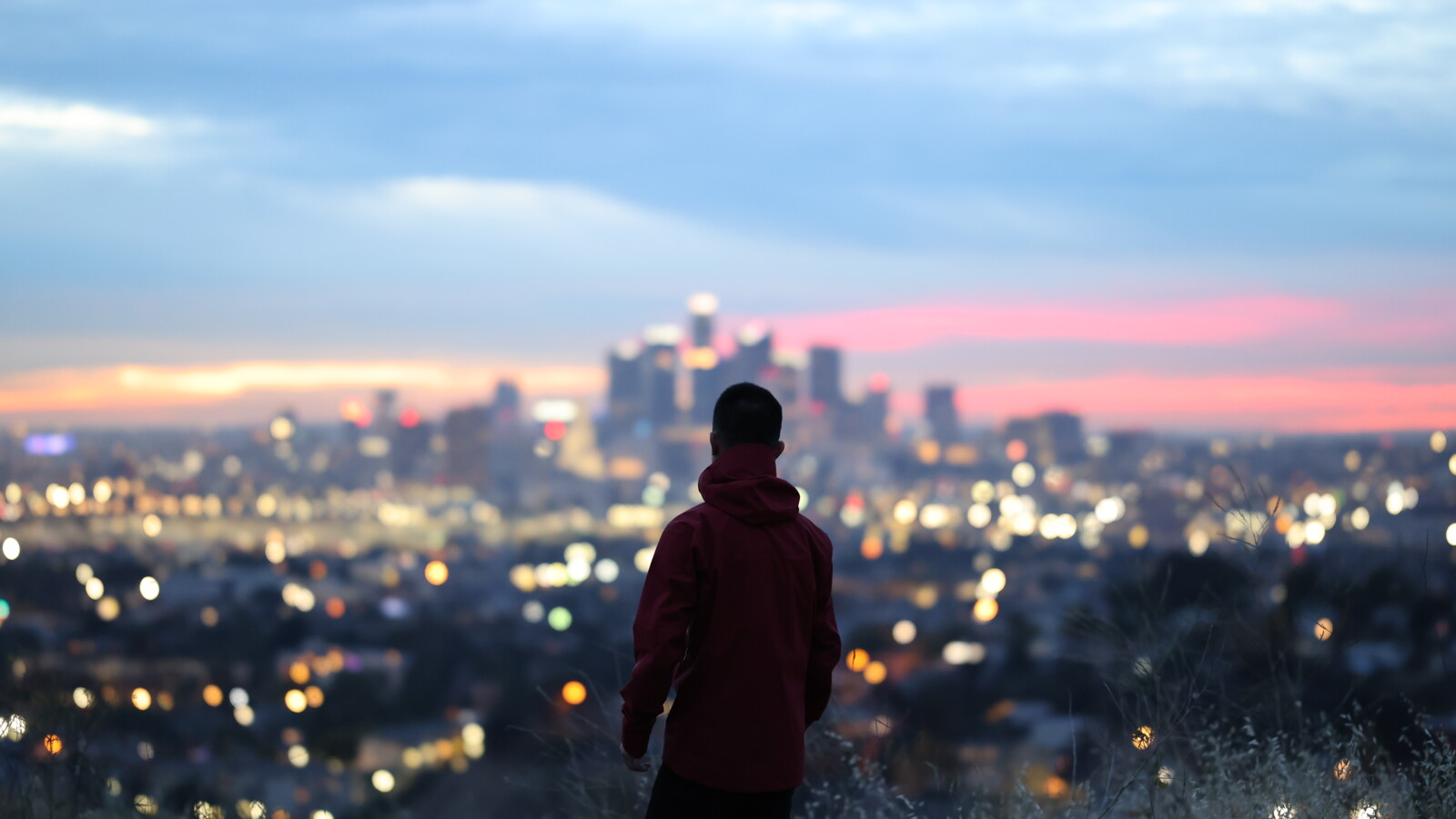 Person overlooking city lights at sunset from hill