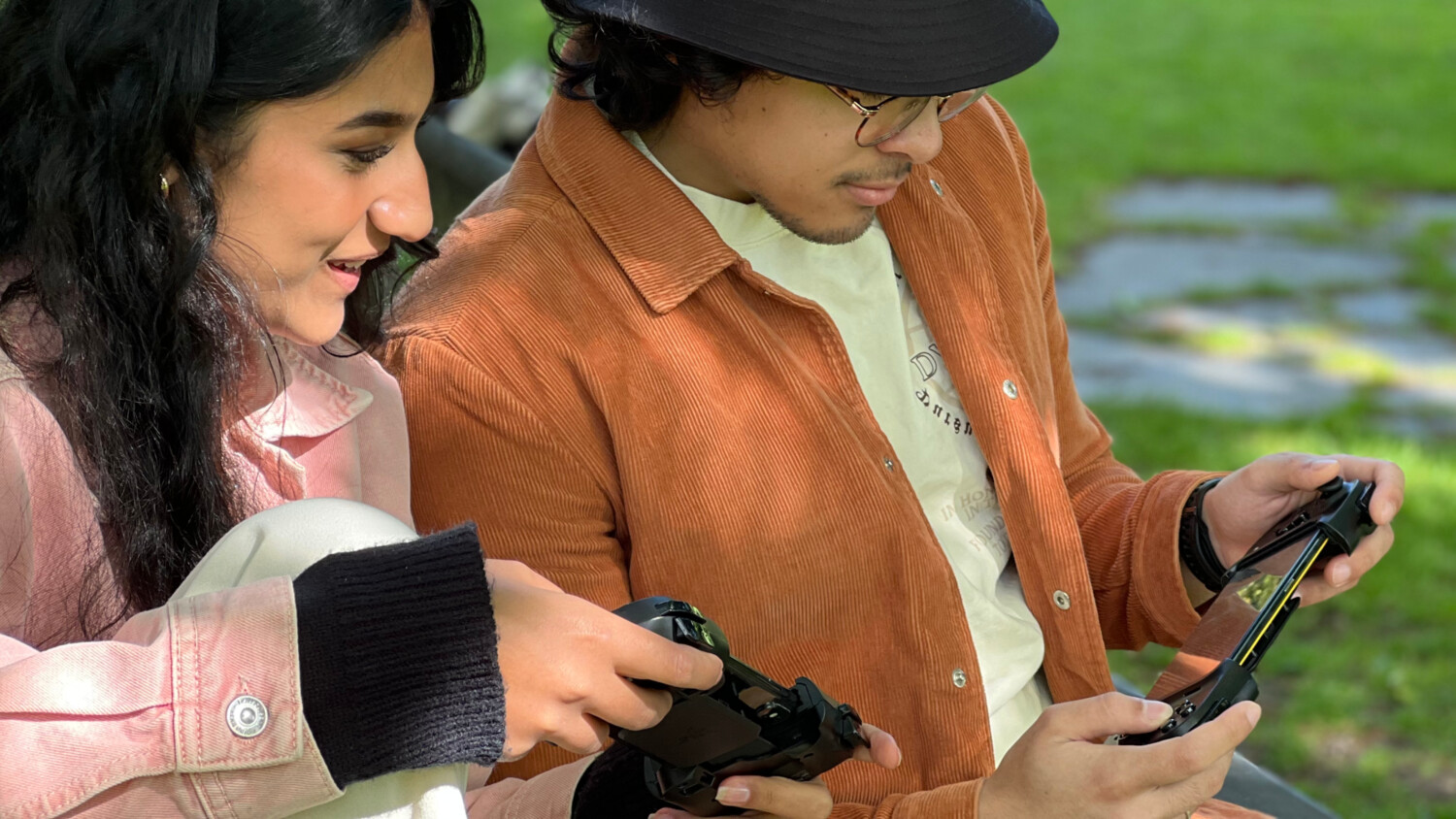 Two people looking at their devices in a field