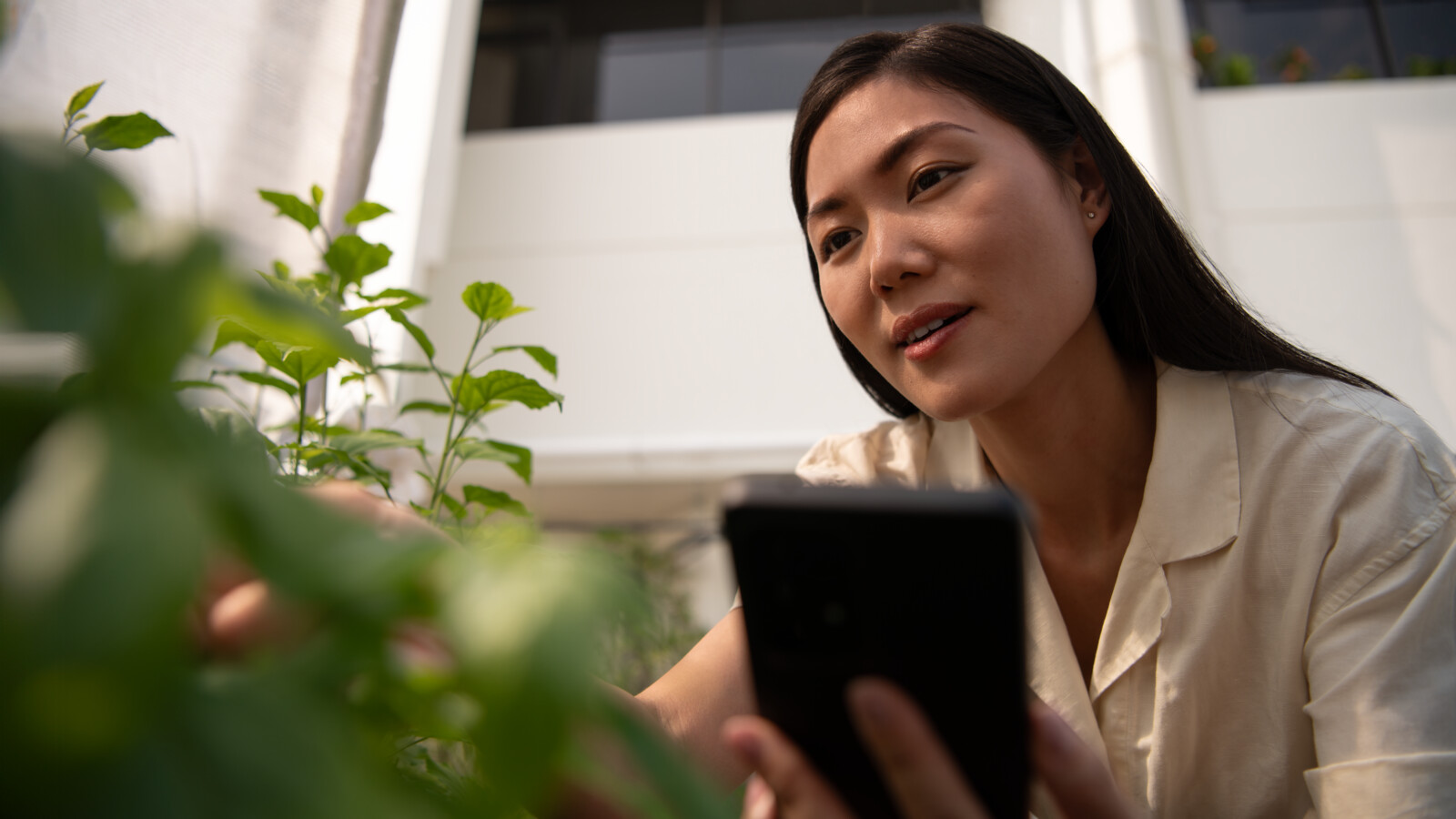 A woman holding a mobile near plants