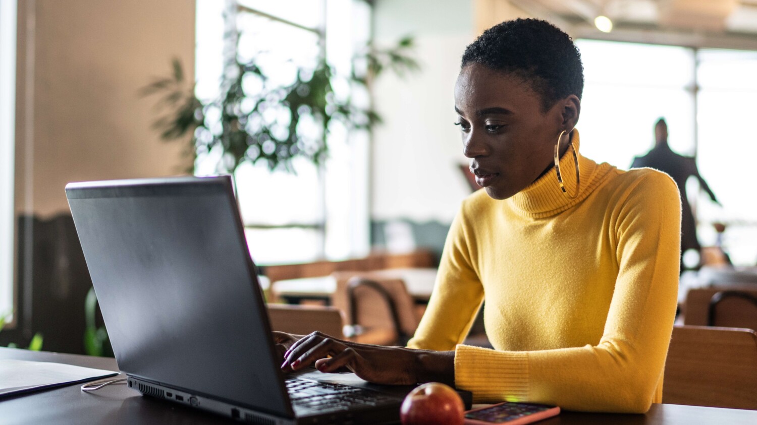 A woman is working on her laptop at a café.