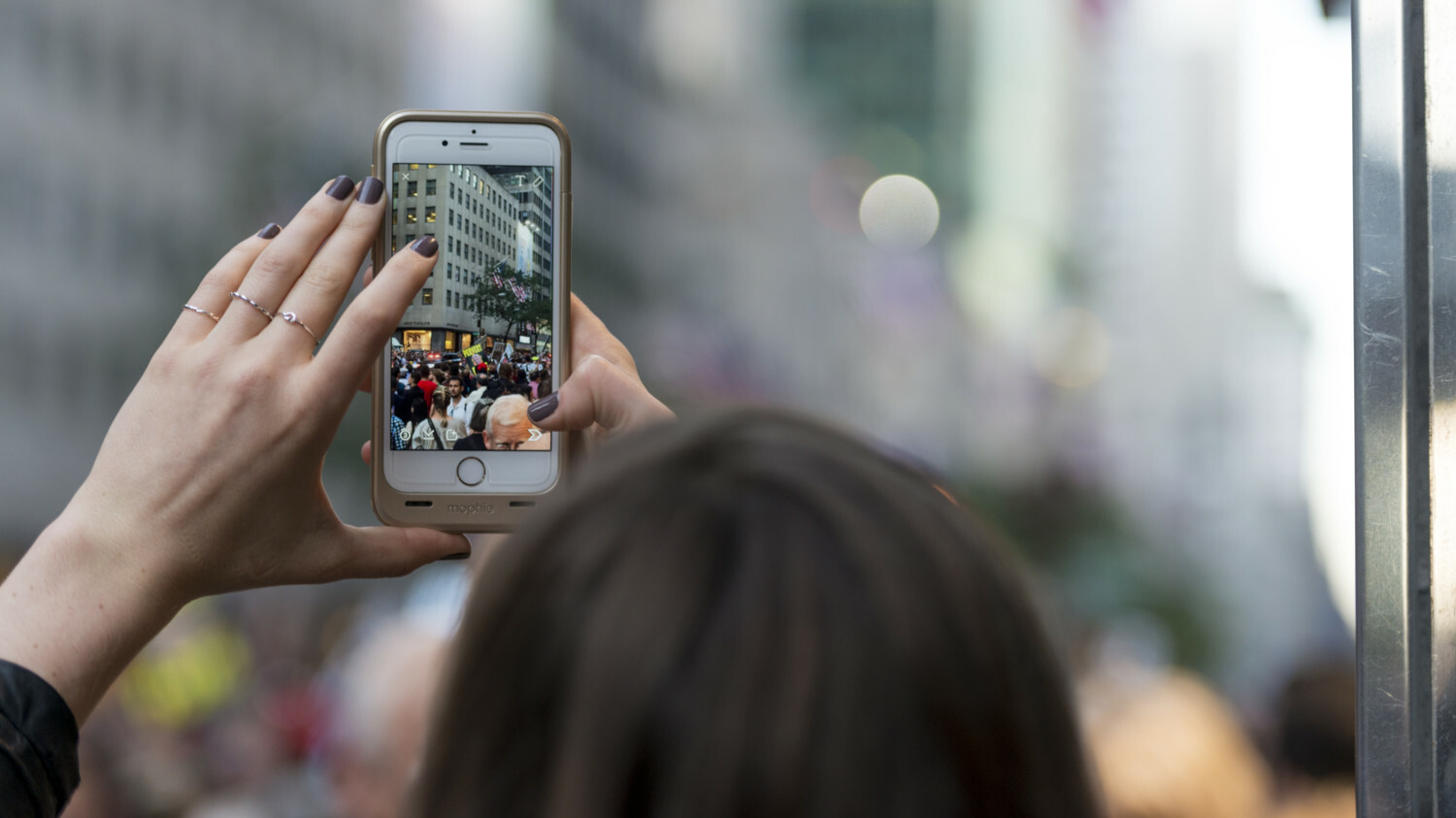 Woman taking photo of crowd in city