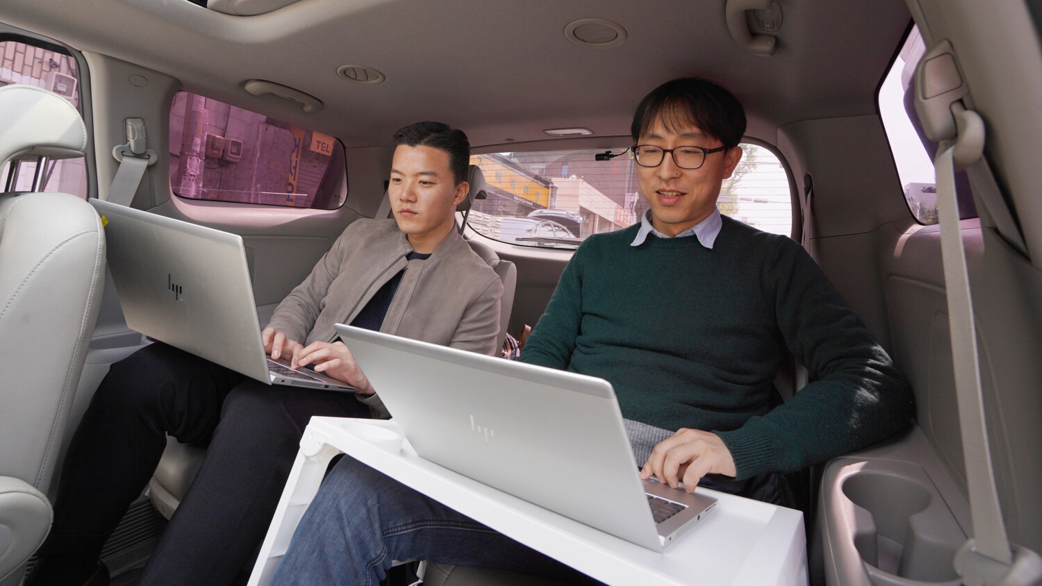 Men in car working on laptops