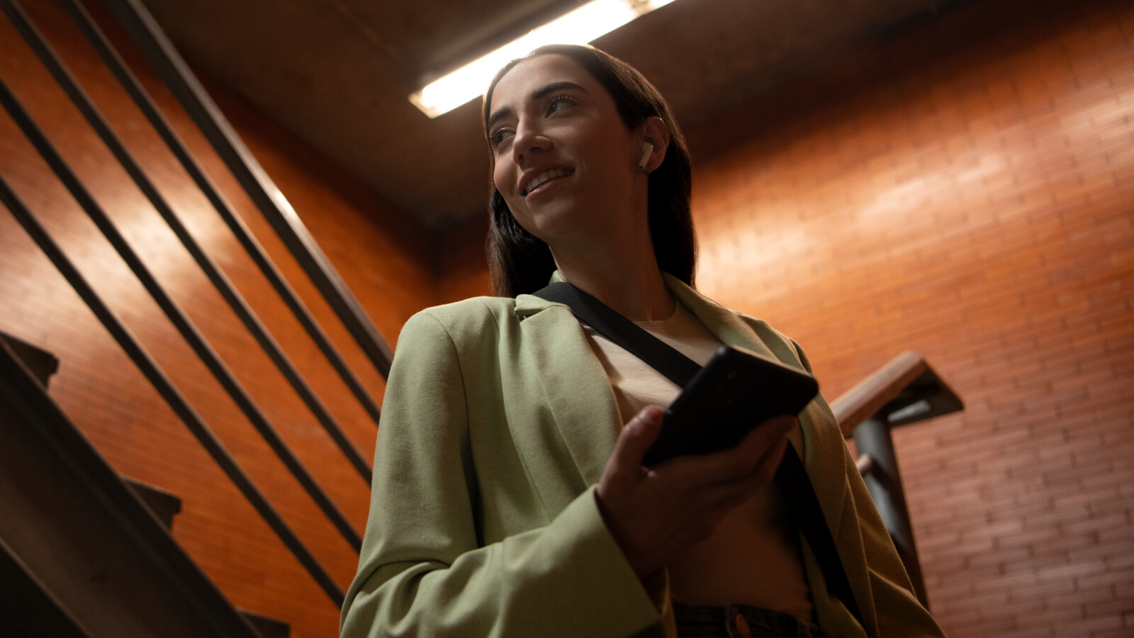 A woman walking down stairs holding a phone.