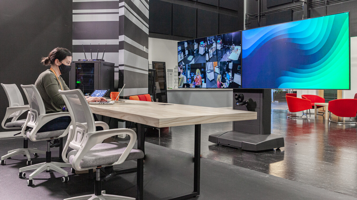 Person at desk with screens in modern control room.