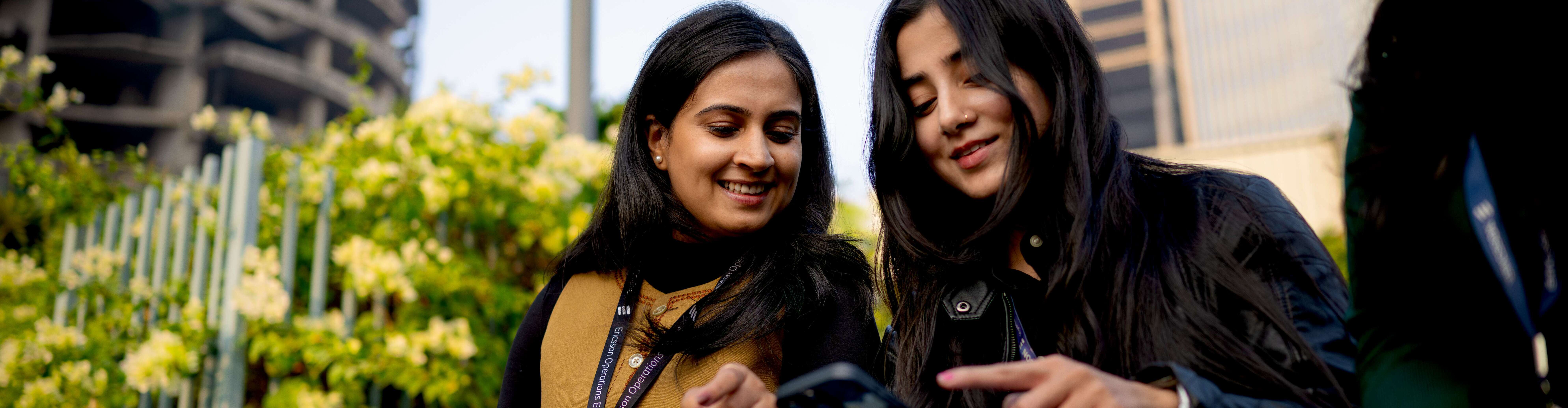 Two women looking at a device.
