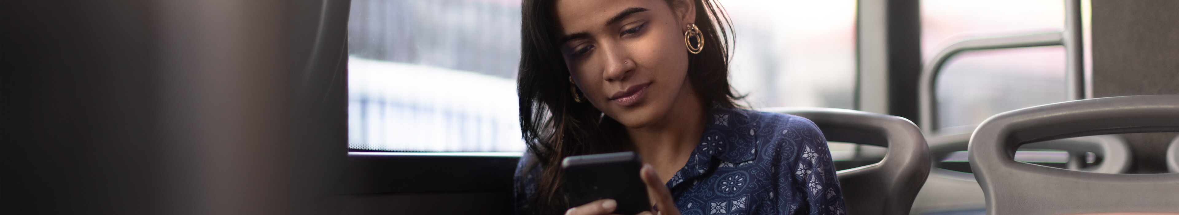 A woman browsing content on a 5GSA connected smartphone on a bus.
