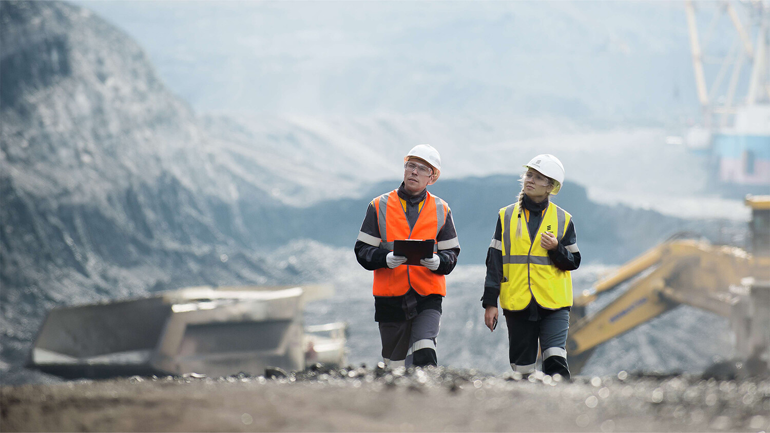 Engineers with tablet walking in an open mine pit. 