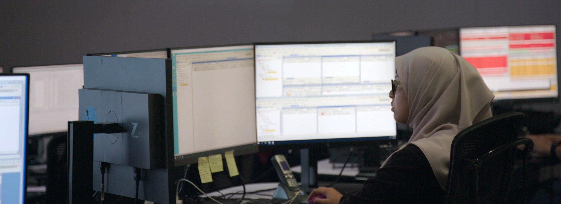 Woman working in front of multiple screens