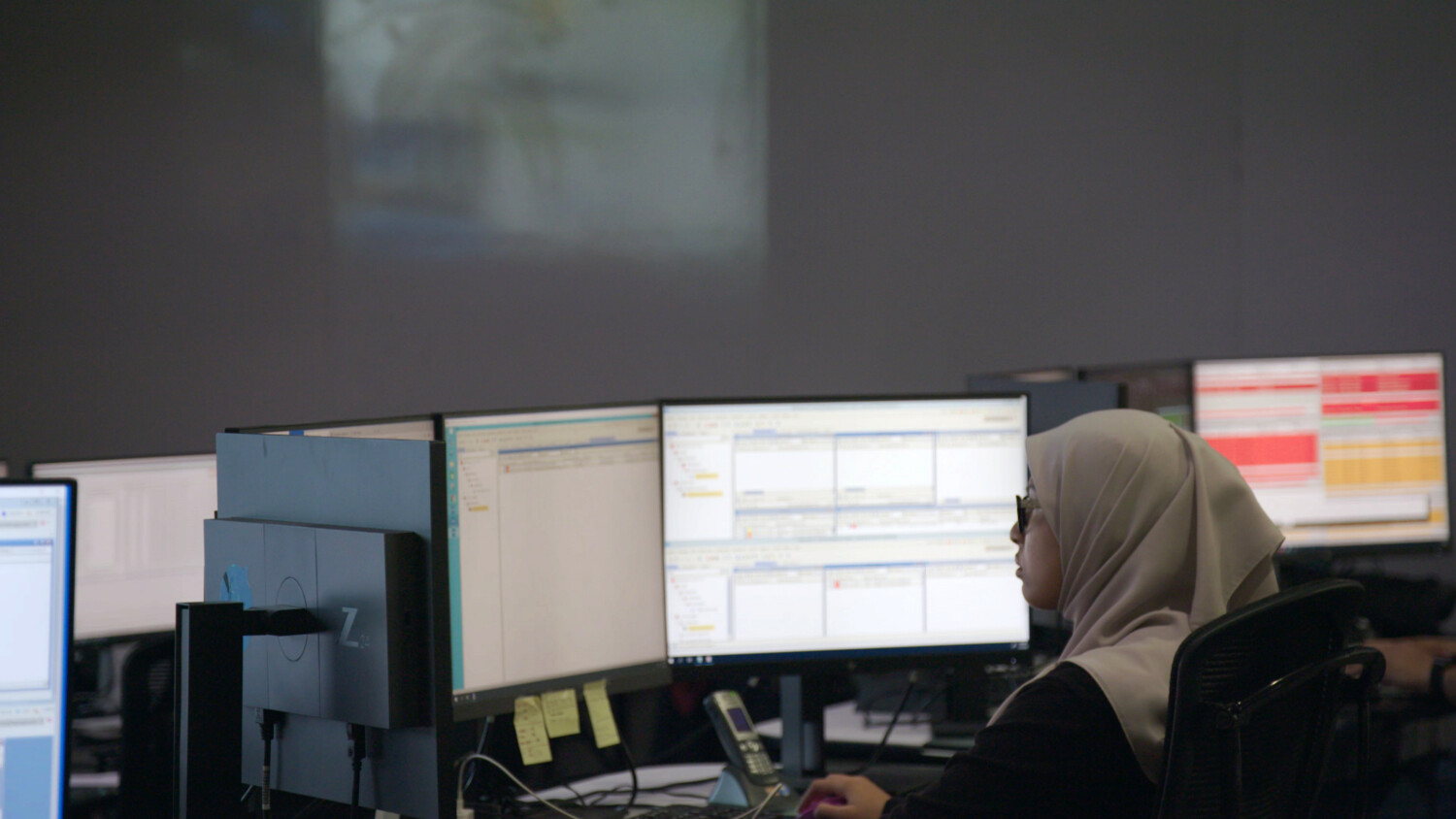Woman working in front of multiple screens