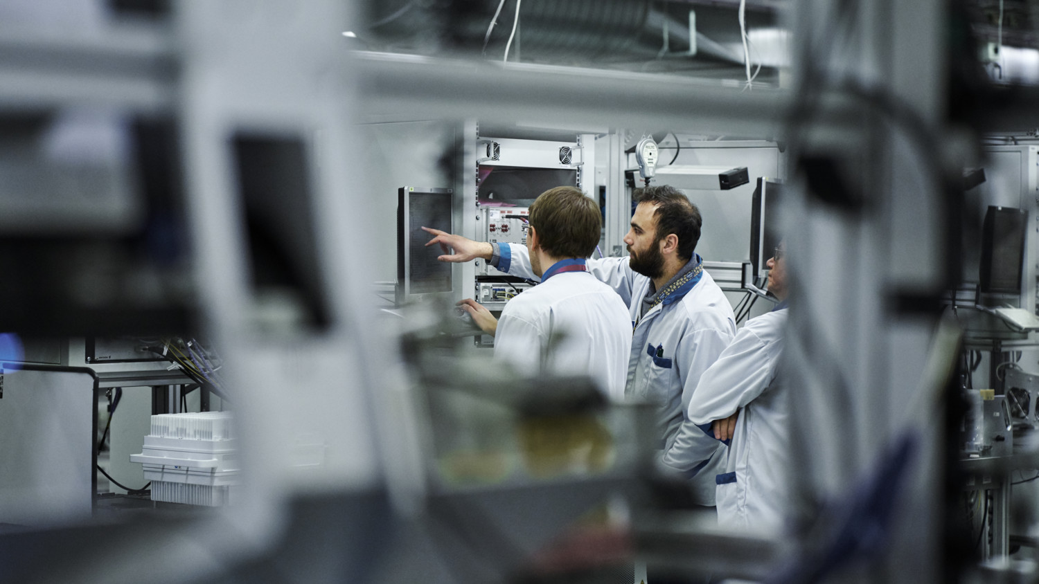 Engineers in factory looking at screens.