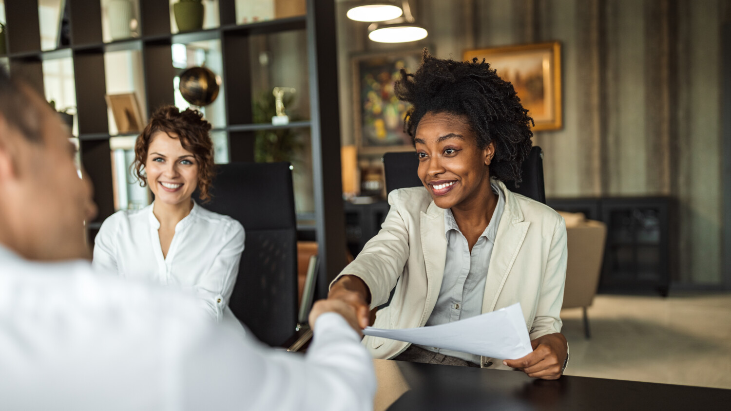 women smiling and shaking hands with a man