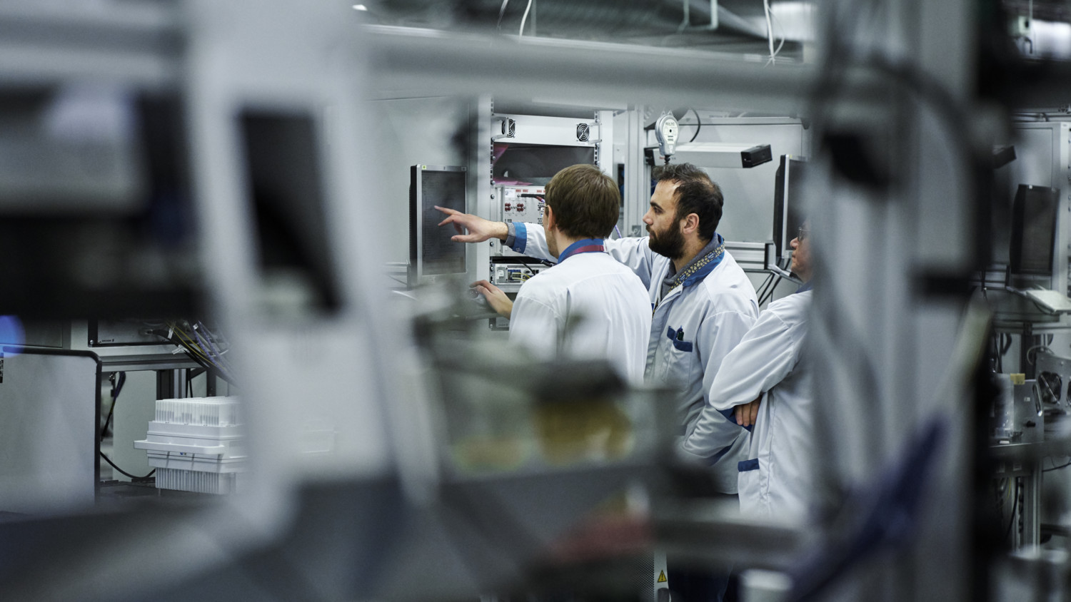 Engineers in factory looking at screens.