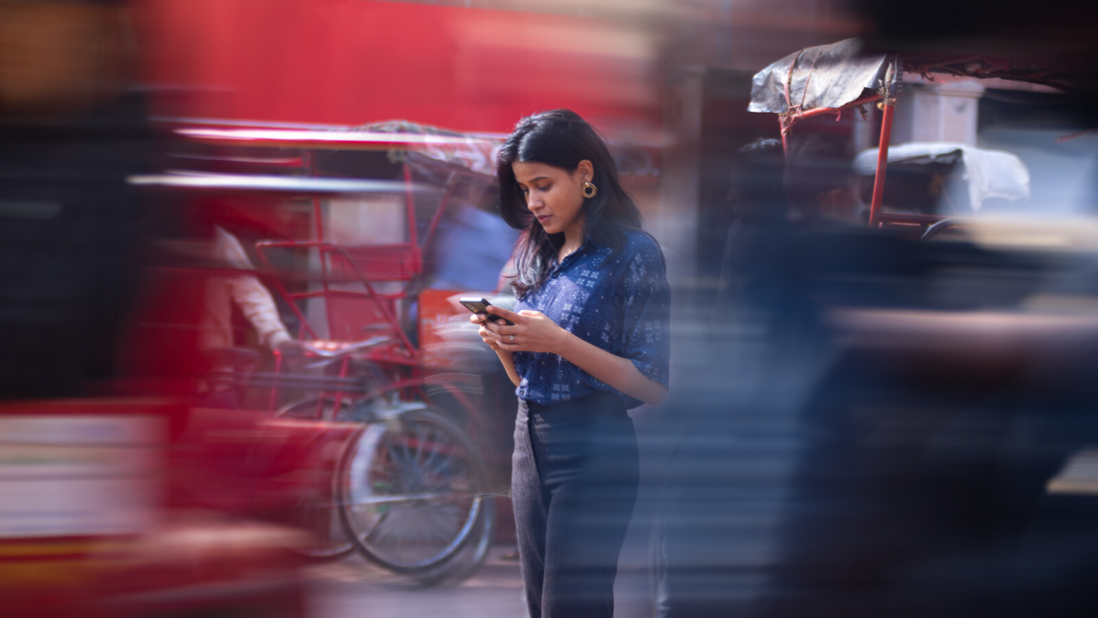 Person using mobile phone in busy urban street.