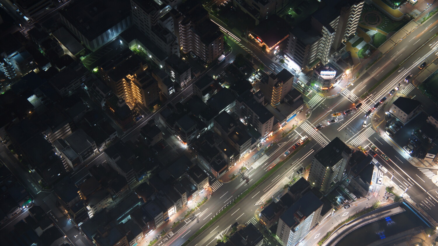 Aerial view of Tokyo at night, buildings and cars on city streets.