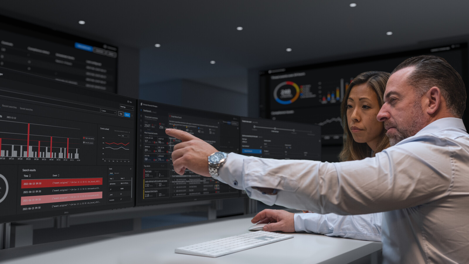 Colleagues inspecting dashboards on multiple screens