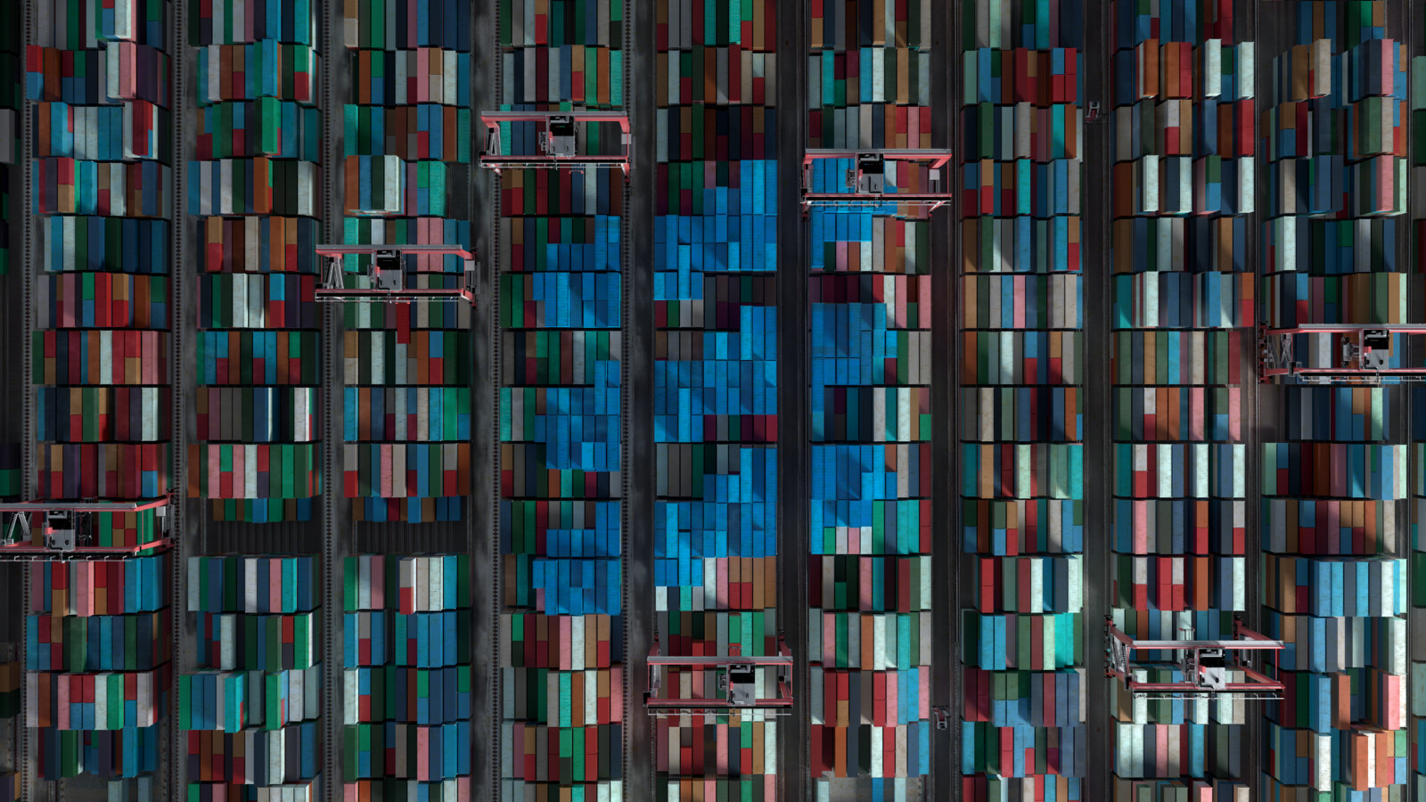 Colorful container stacks in a port. Blue containers are arranged to form the Ericsson logo.