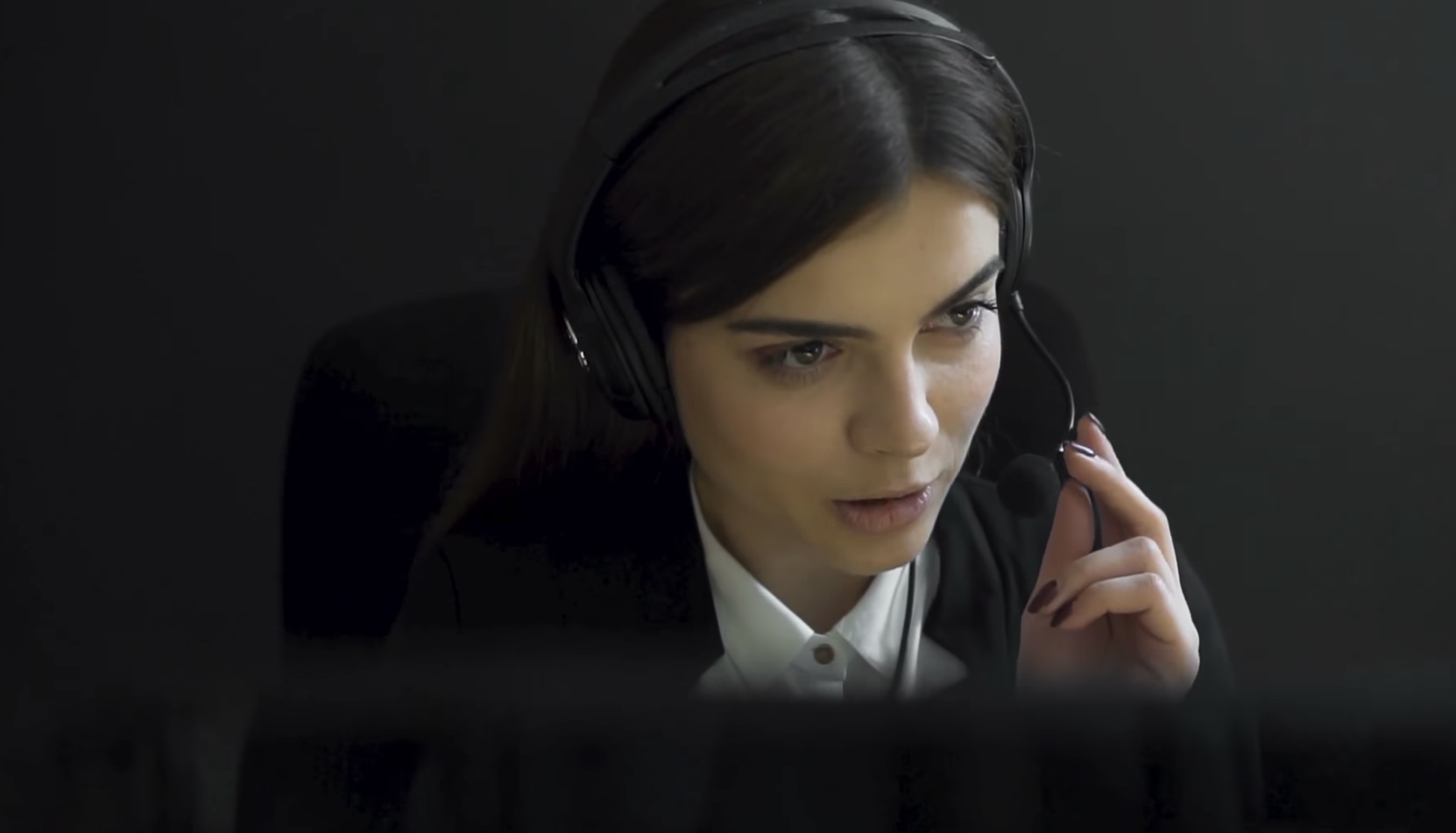 Person with headset in front of computer screen.