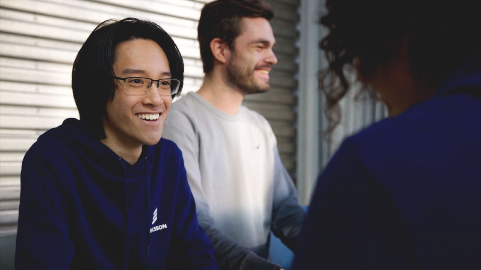 Man in Ericsson pullover talking with a colleague