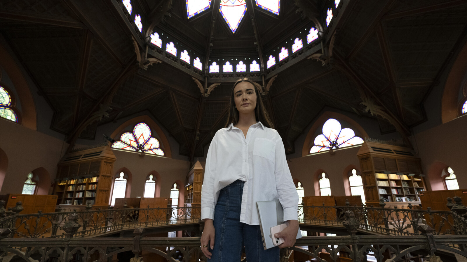 A woman standing inside a building with laptop.