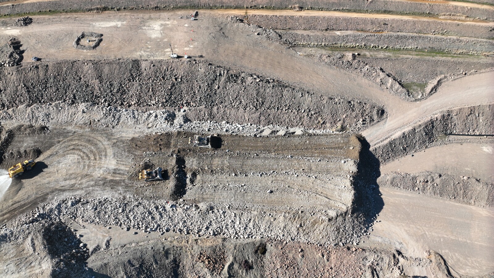 Top-down view of a bulldozer leveling the soil on a construction site.