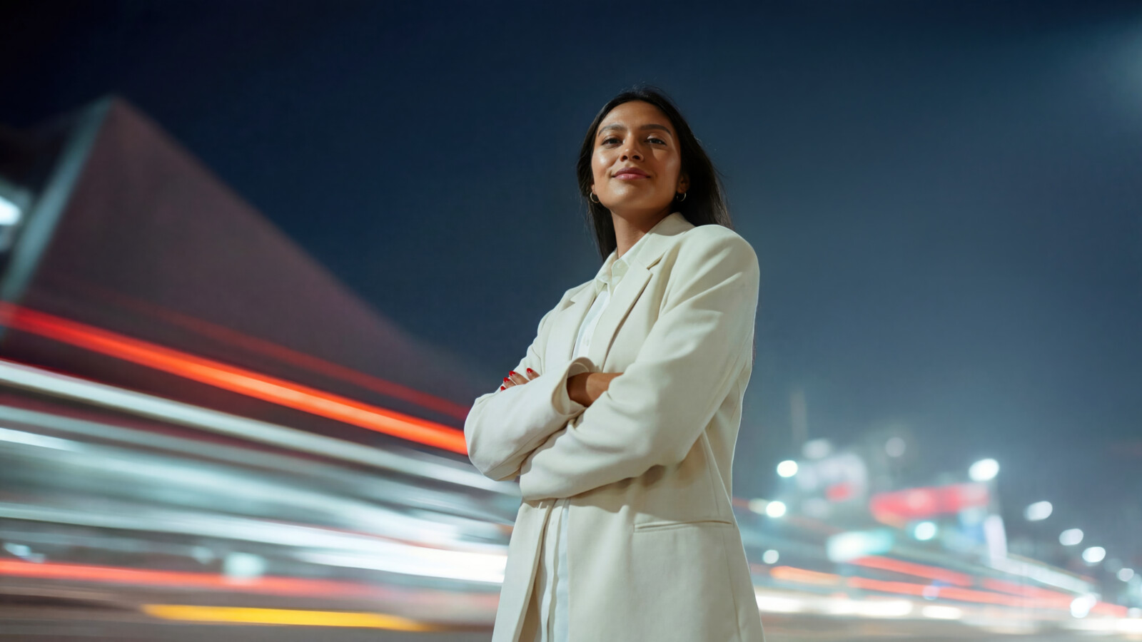 Confident woman standing in city at night with motion lights