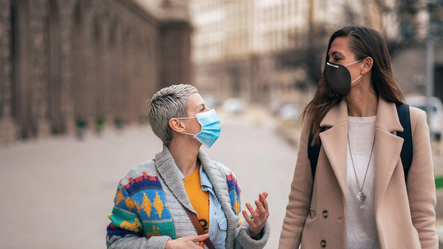Two women during the pandemic wearing masks talking.