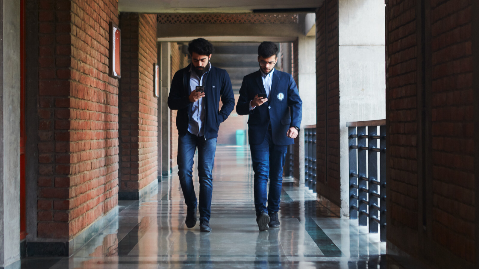 Students walking on a corridor whiling looking at phone